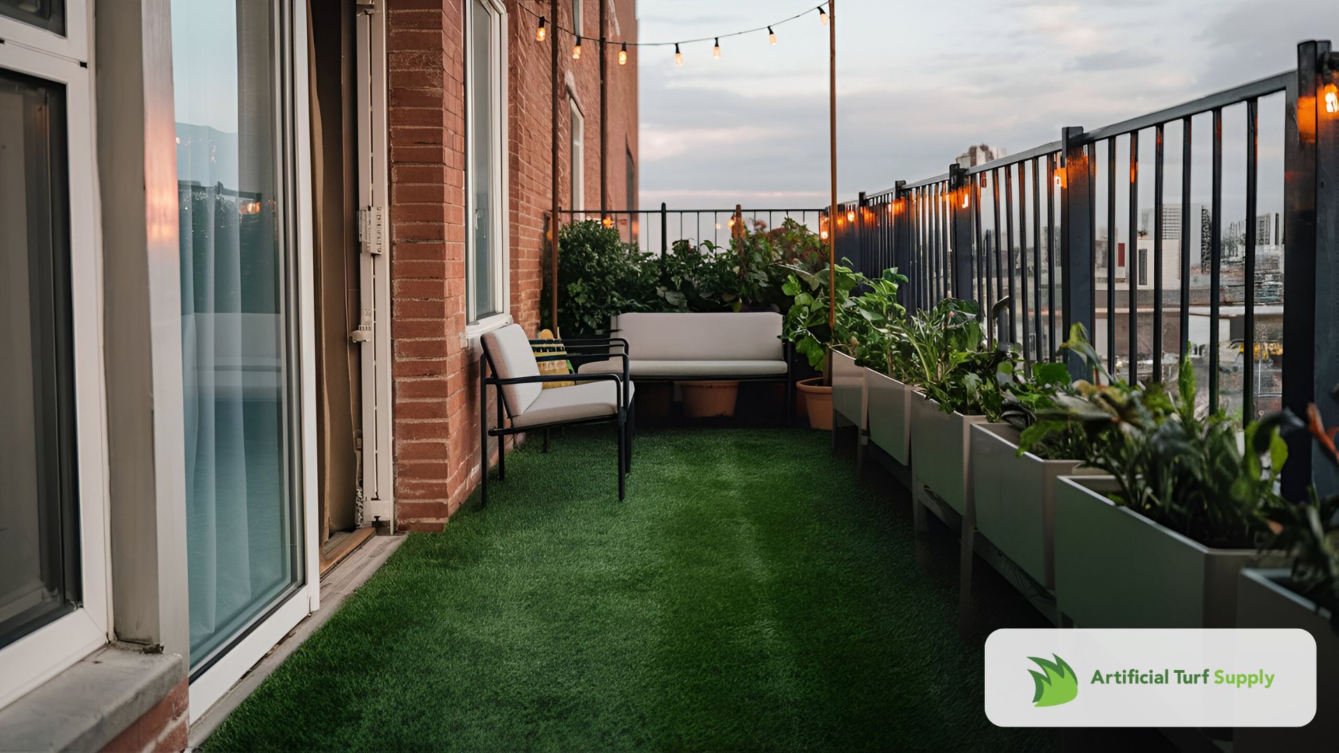 A small city apartment balcony with a vibrant green artificial grass rug covering the concrete floor